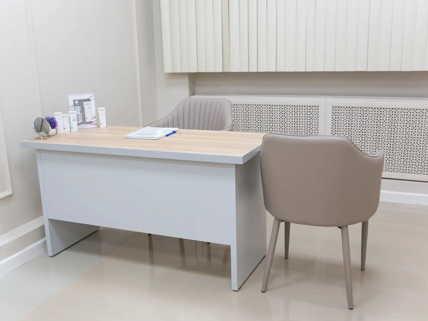 Consultório claro com mesa e cadeira estofada
