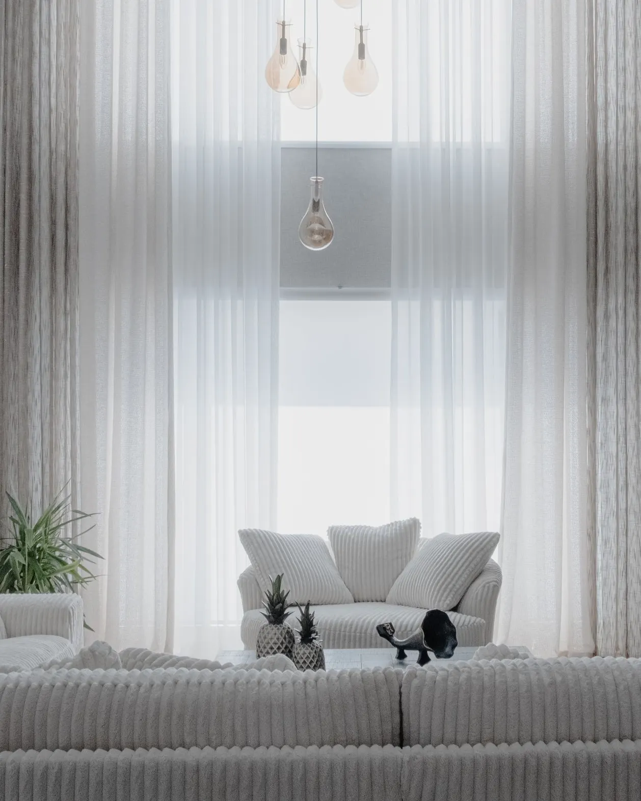 Sala de estar clara com sofás brancos e cortinas longas